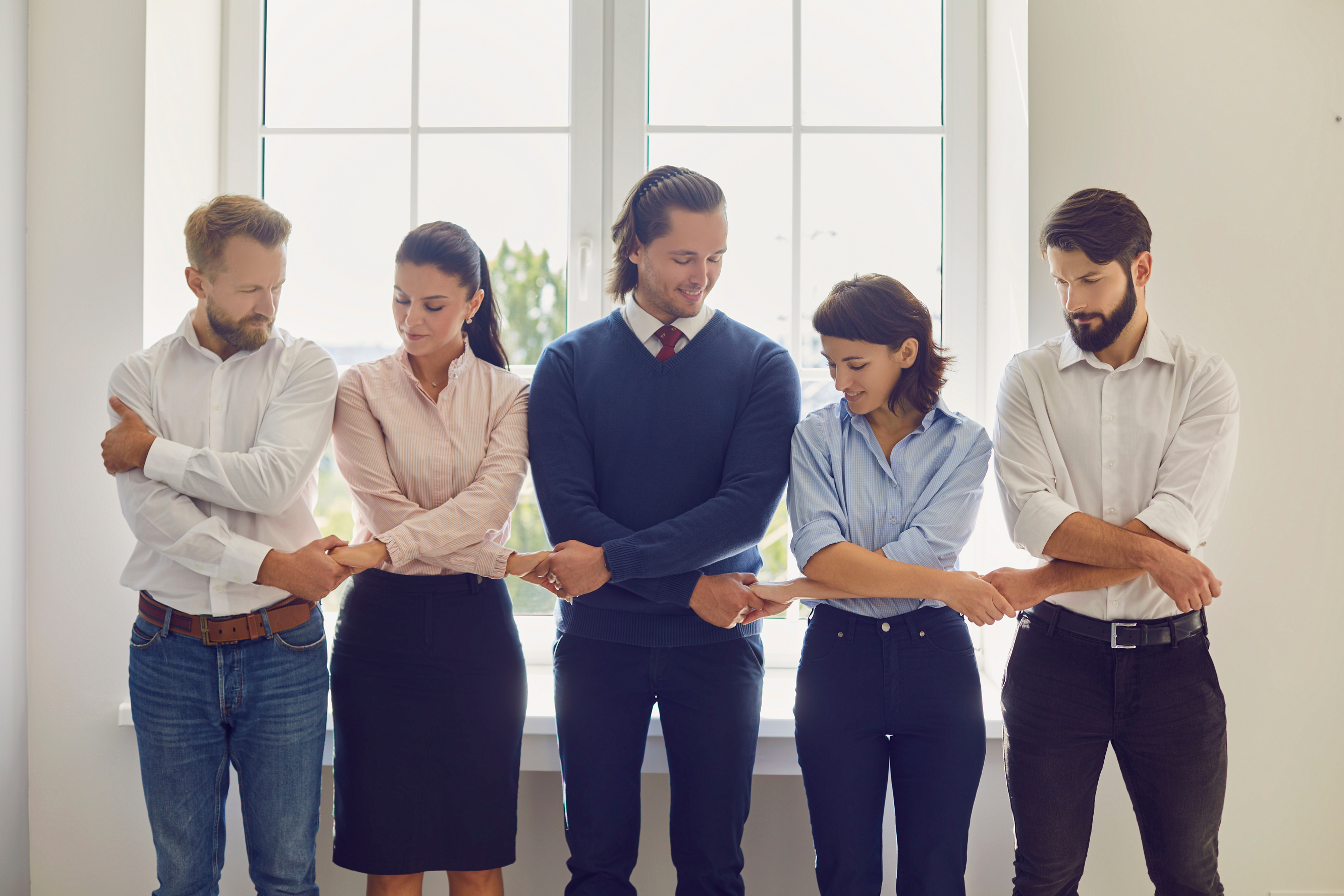 Positive Office Employees Standing in a Row Holding Hands Supporting Each Other